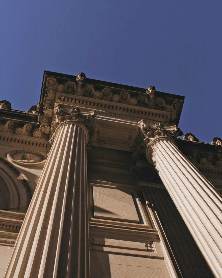Classical courthouse columns against a blue sky
